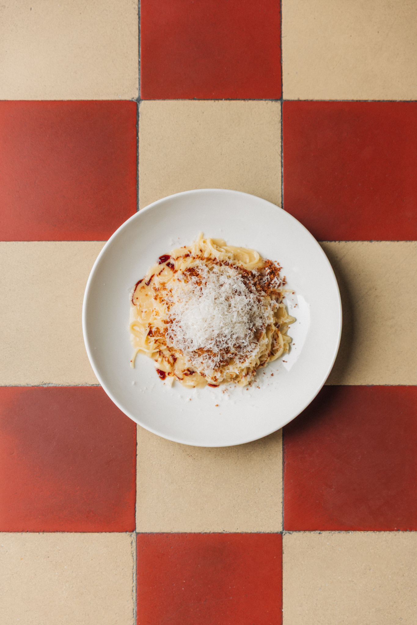 Pasta mit Käse und Chiliöl auf kariertem Fliesenboden